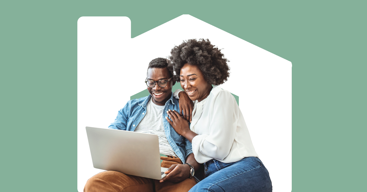A couple smiling while looking at a laptop.